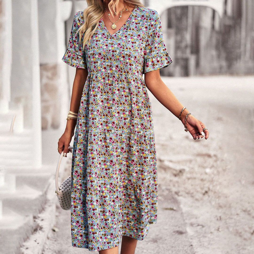 Robe d'été fleurie pour femme, manches courtes, col en V, fond urbain flou. Mode féminine, tenue décontractée, style estival tendance.