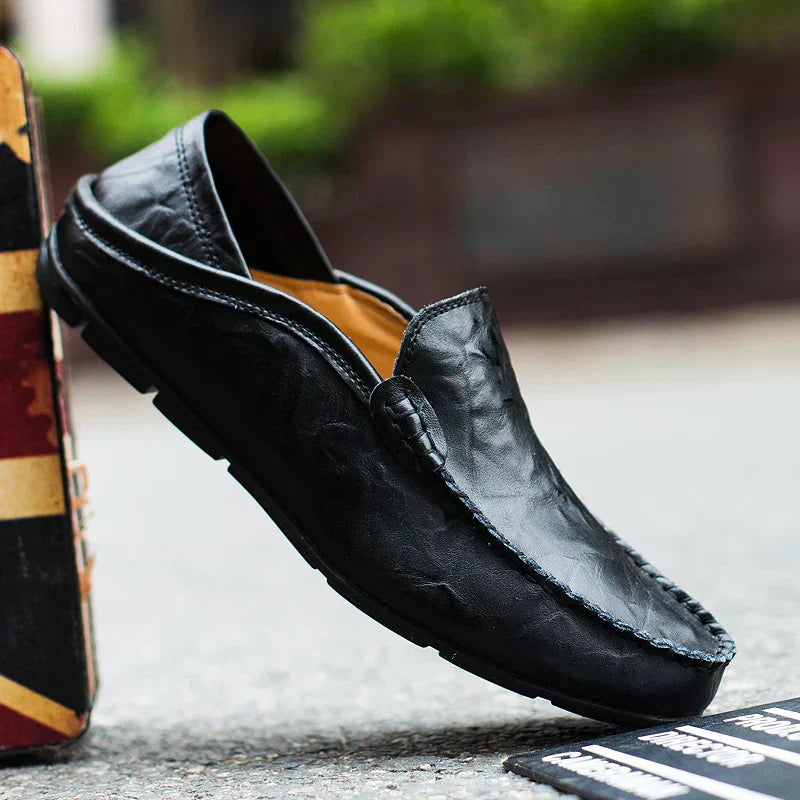 Mocassin en cuir noir pour homme, élégant et confortable, posé sur une boîte. Chaussure décontractée idéale pour un style moderne et raffiné.