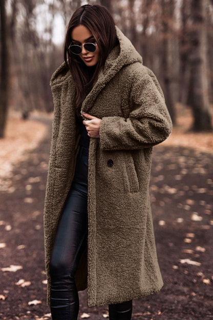 Femme portant un manteau en fausse fourrure marron, lunettes de soleil, dans un parc automnal. Mode hiver, style chic, tendance.