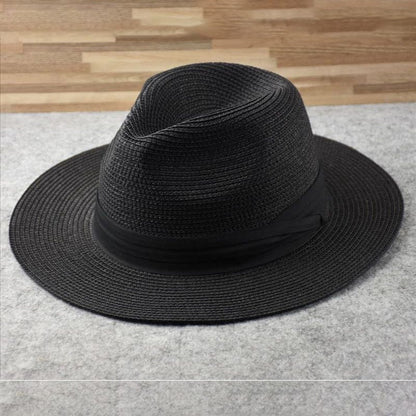 Chapeau Fedora noir en paille tressée sur fond gris, élégant et tendance, idéal pour un look chic et décontracté. Accessoire mode intemporel.