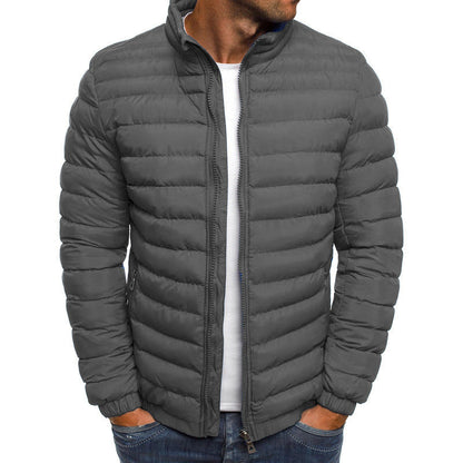 Homme portant une doudoune grise matelassée, fermeture éclair, col montant, poches latérales, style décontracté, mode hiver.