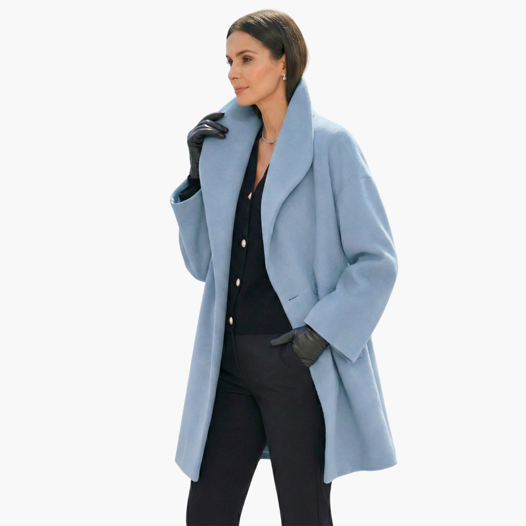 Femme portant un manteau bleu élégant, gants noirs et tenue chic. Mode automne-hiver, style moderne et sophistiqué.