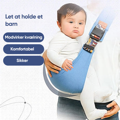 Bébé dans un porte-bébé bleu, sécurisé et confortable, avec texte en danois sur la sécurité et le confort. Accessoire parental pratique et sûr.