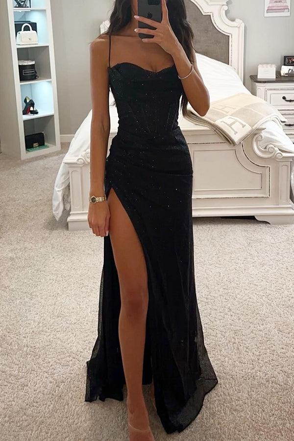 Robe de soirée noire élégante avec fente haute, portée par une femme dans une chambre moderne. Mode féminine, tenue de soirée chic.