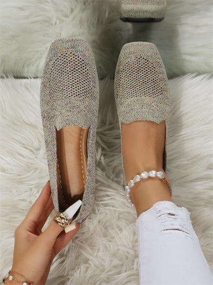 Chaussures plates en tricot beige sur tapis blanc, portées avec un jean blanc déchiré et un bracelet de perles. Mode féminine élégante et décontractée.