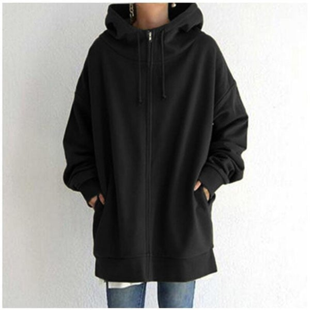 Veste à capuche noire unisexe, ample et zippée, avec poches avant, portée par une personne en jean. Mode décontractée, tendance automne-hiver.