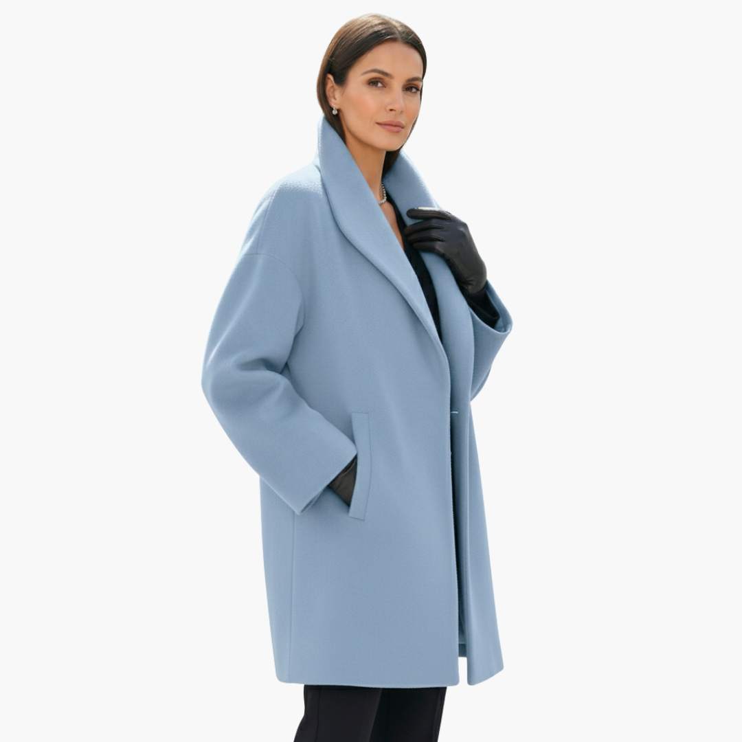Femme portant un manteau bleu clair élégant, col châle, avec gants noirs. Mode automne-hiver, style chic et moderne.