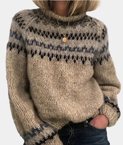 Femme portant un pull en laine tricoté à motifs nordiques, col roulé, avec un pendentif doré, style hiver, mode cosy et tendance.