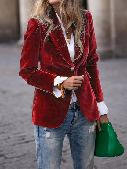 Femme en blazer rouge en velours, chemise blanche, jean déchiré, tenant un sac vert. Mode élégante, tenue décontractée chic, style urbain.