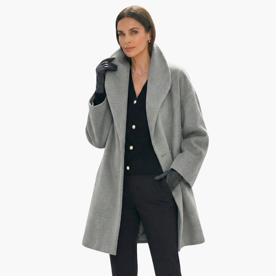 Femme portant un manteau gris élégant, gants noirs et chemise noire avec boutons dorés. Mode automne-hiver, style chic et sophistiqué.
