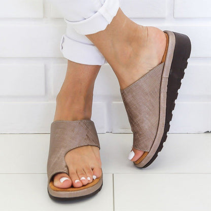 Sandali donna beige con zeppa, design aperto, suola antiscivolo, indossati su pavimento bianco. Calzature estive comode ed eleganti.