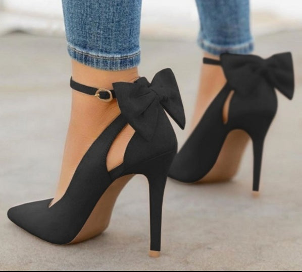 Escarpins noirs à talons hauts avec nœuds, portés avec un jean. Chaussures élégantes pour femmes, mode tendance, style chic et sophistiqué.