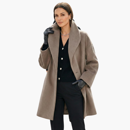 Femme élégante portant un manteau en laine beige, gants noirs et cardigan noir, posant avec confiance. Mode automne chic, style sophistiqué.