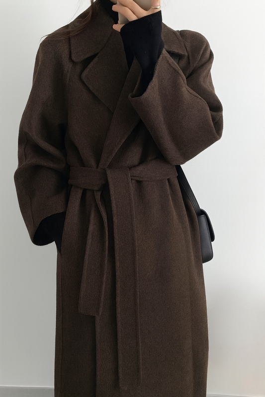 Manteau long marron en laine ceinturé, porté par une personne, style élégant et hivernal, mode automne-hiver, vêtement chaud et tendance.