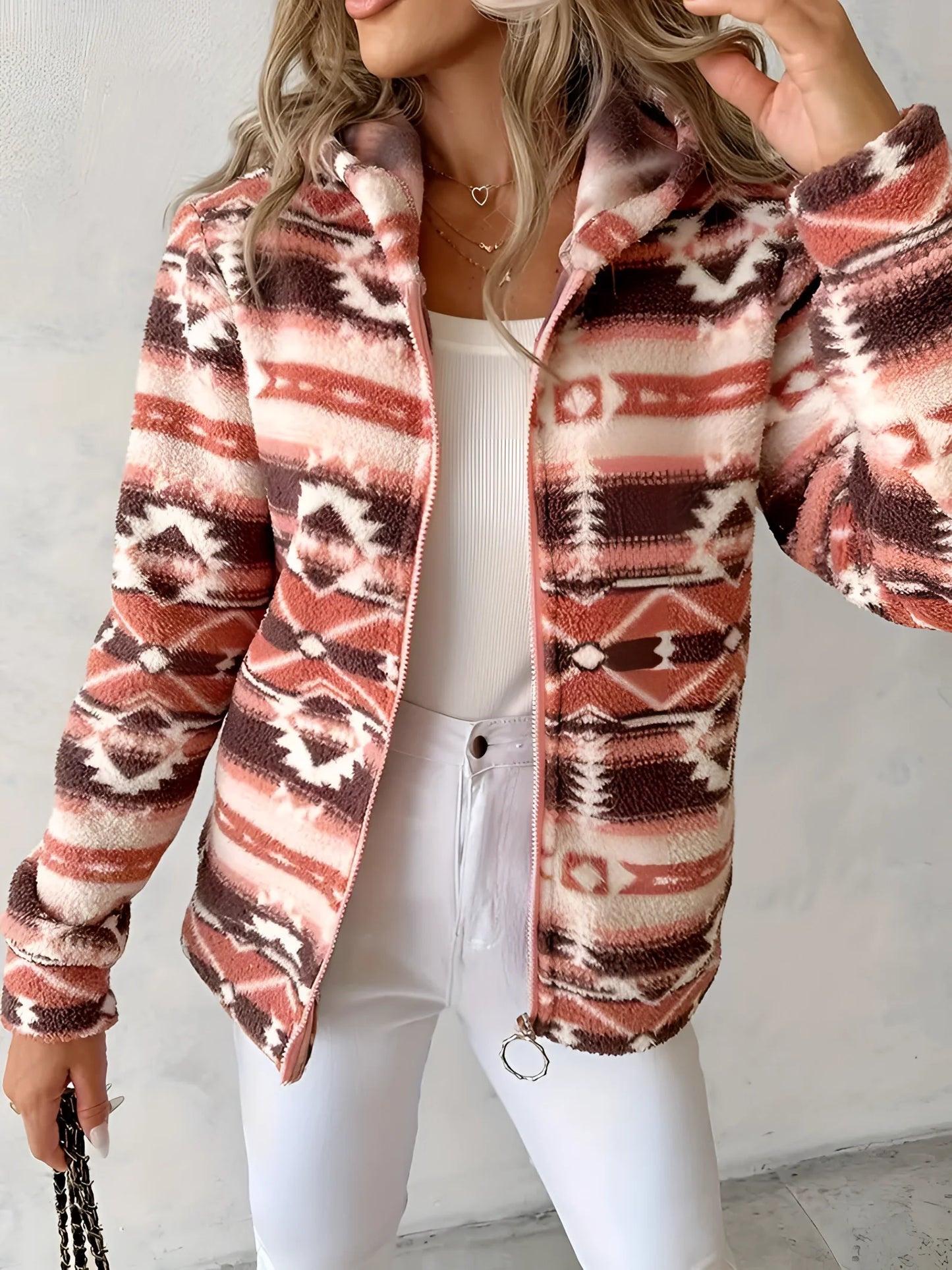 Woman wearing a cozy Southwestern-style plush fleece zip-up jacket in an outdoor setting. The jacket features a soft fleece material and distinctive Southwestern patterns, providing warmth and comfort. The focus is on the upper body, highlighting the jacket's design and texture.