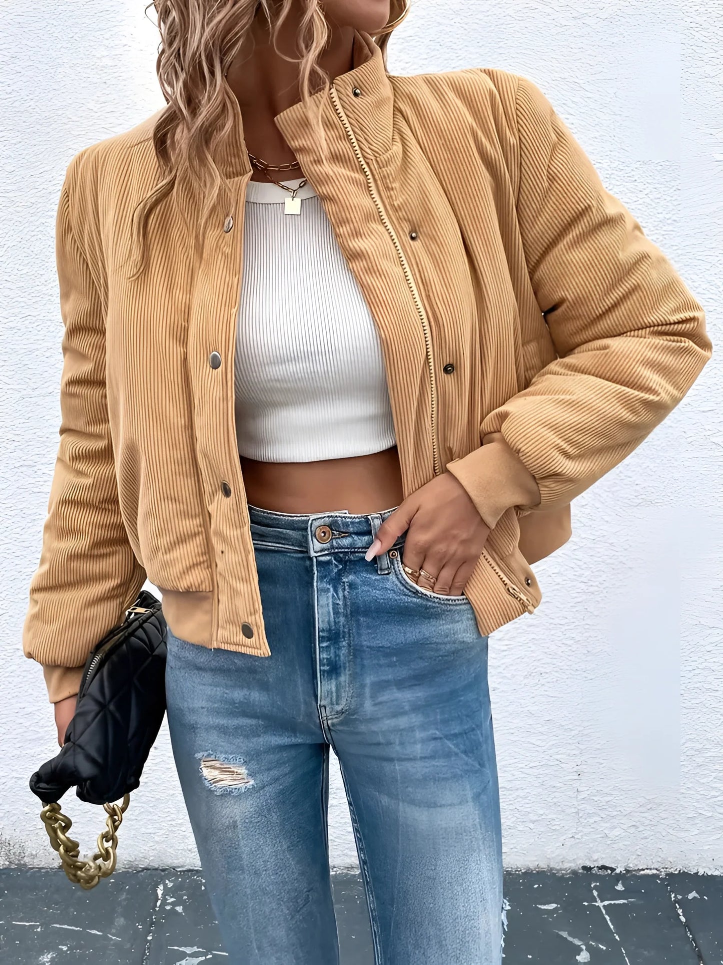 Tan corduroy bomber jacket for women displayed on a model wearing casual jeans and a dress shirt. The jacket features a trendy fall design with a relaxed fit, showcasing details like long sleeves and a high neckline. Its beige color and textured fabric make it a stylish choice for outerwear.