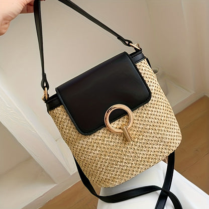 Sac à bandoulière en paille tressée avec rabat en cuir noir et boucle dorée, posé sur une surface en bois clair. Accessoire mode tendance.