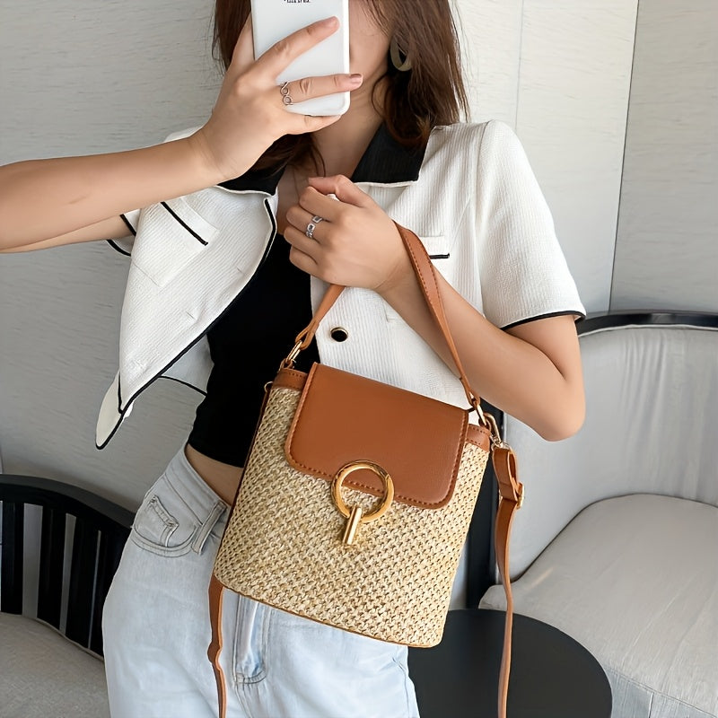 Femme tenant un sac à main en paille tressée avec rabat en cuir marron et boucle dorée, mode estivale élégante, tenue décontractée chic.