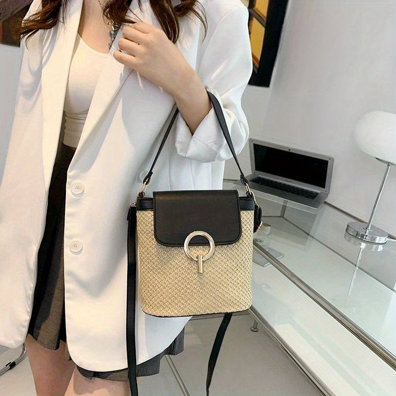 Sac à main en paille tressée avec rabat noir et boucle métallique, porté par une femme en blazer blanc. Accessoire mode élégant et tendance.