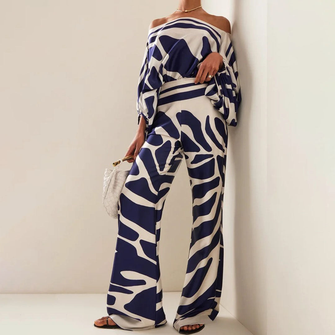 Tenue élégante femme, combinaison ample à motifs bleus et blancs, épaules dénudées, sac à main blanc, mode chic et moderne, style tendance.