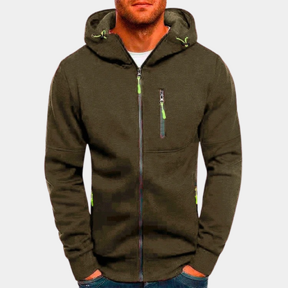 Homme portant un sweat à capuche zippé kaki avec poches et détails verts, mode décontractée, vêtement tendance pour homme, style urbain.