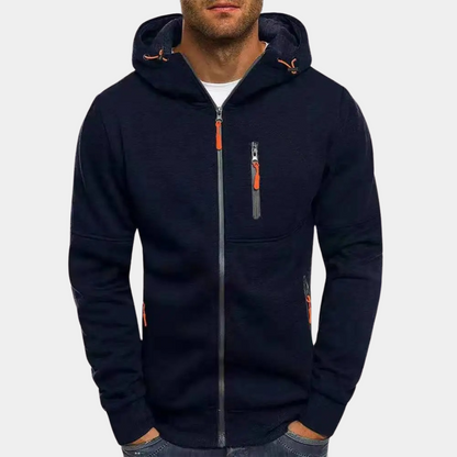 Homme portant un sweat à capuche noir zippé avec poches et détails orange, mode décontractée, vêtement tendance pour homme, style urbain.