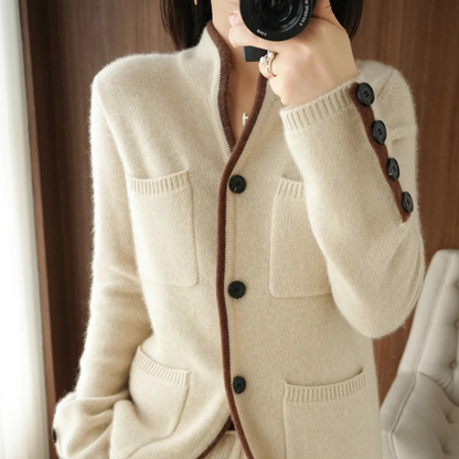 Beige cardigan med sorte knapper og lommer, elegant design, kvinde fotograferer sig selv, moderne mode, stilfuldt tøj, indendørs.