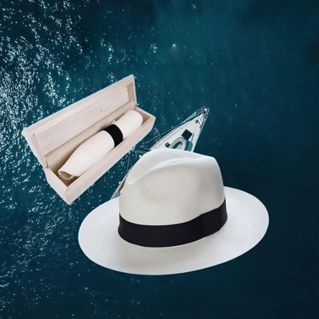 Chapeau Panama blanc avec ruban noir, boîte en bois et pochette, flottant sur fond océanique bleu. Accessoire élégant, mode estivale.