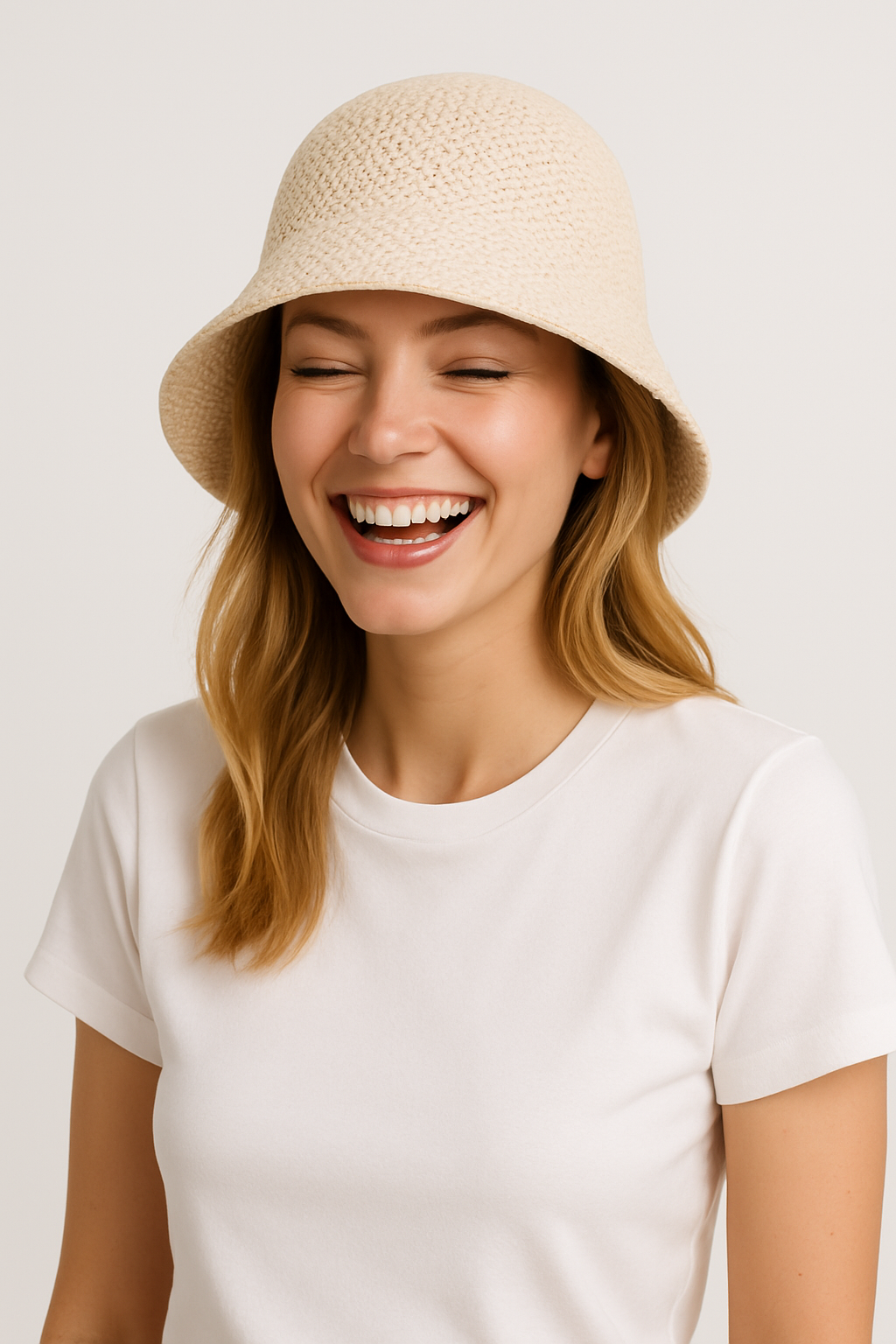 Femme souriante portant un chapeau en paille beige et un t-shirt blanc. Mode estivale, accessoire tendance, style décontracté.