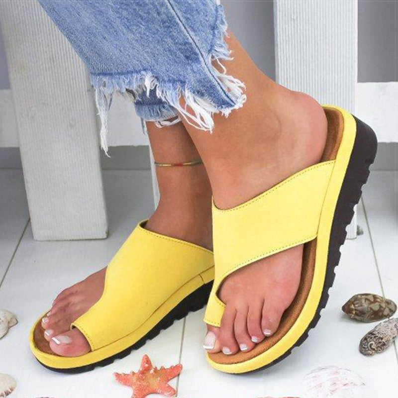 Sandali gialli da donna con suola nera, indossati con jeans strappati. Design estivo, comodi e alla moda, perfetti per la spiaggia.