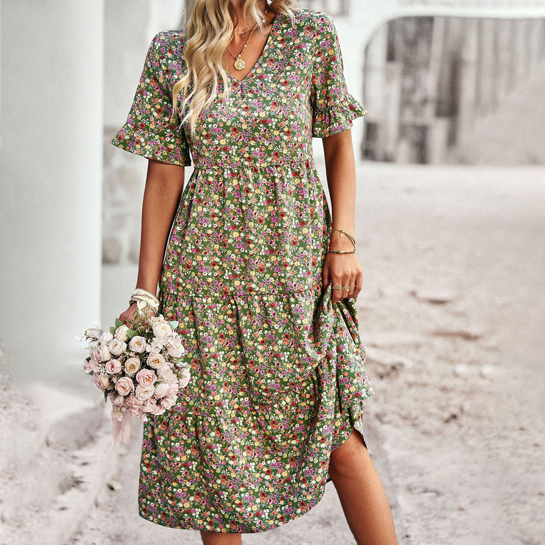 Robe fleurie bohème chic, manches courtes, femme tenant bouquet de roses, style décontracté, fond urbain. Mode été tendance.