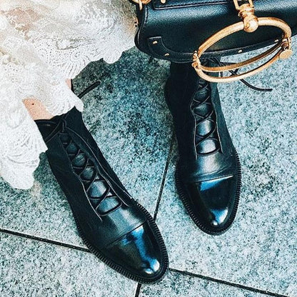 Schwarze Lederstiefel mit Schnürung, Damenmode, elegante Schuhe, auf grauem Boden.