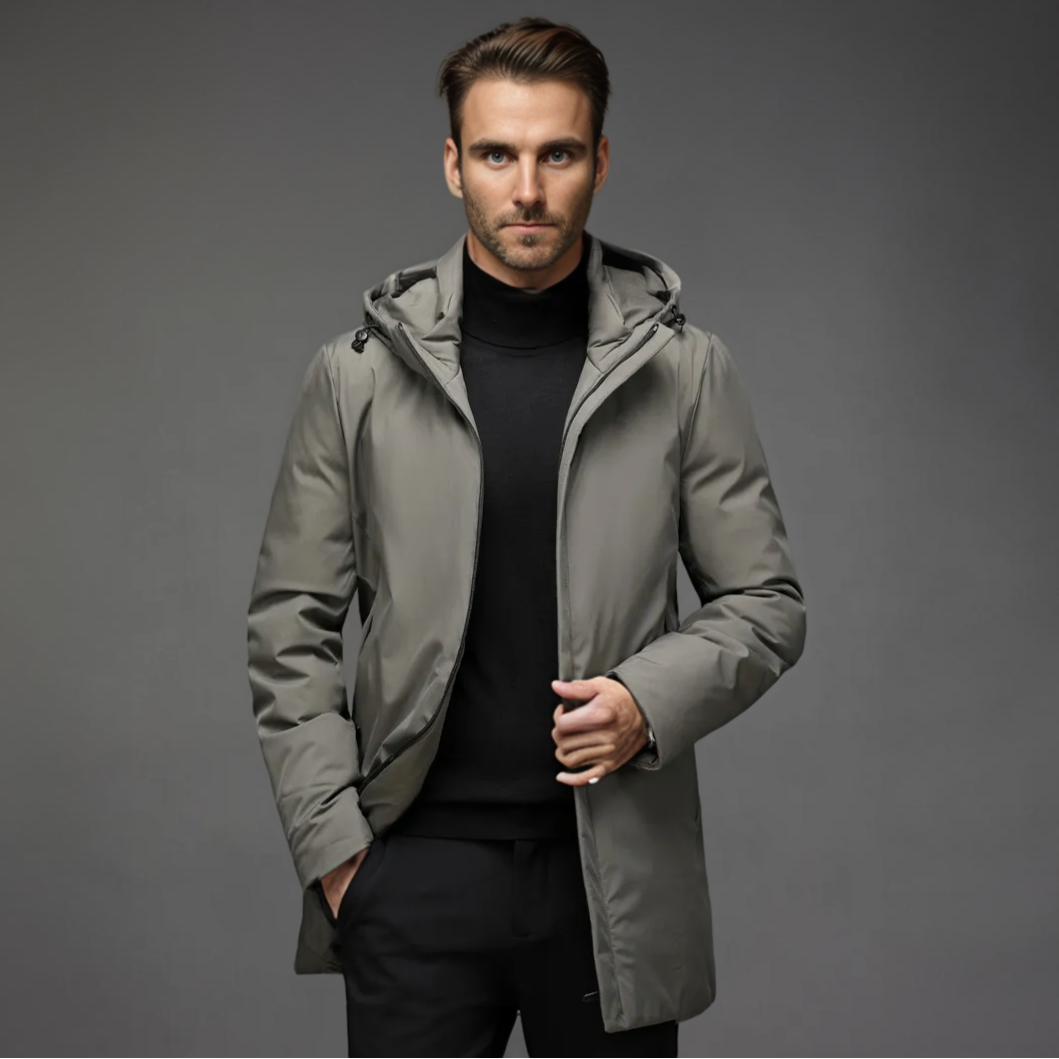 Homme portant un manteau gris élégant avec capuche, sur fond gris. Mode masculine, veste d'hiver, style moderne et chic.