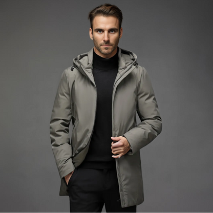 Homme portant un manteau gris élégant avec capuche, sur fond gris. Mode masculine, veste d'hiver, style moderne et chic.