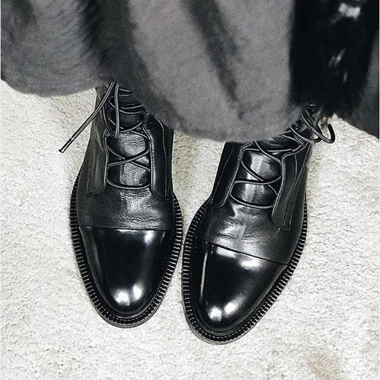 Schwarze Lederstiefel mit Schnürung auf hellem Teppich, elegante Herrenschuhe.