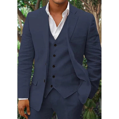 Homme en costume bleu marine élégant avec gilet, chemise blanche, posant devant un fond de verdure. Mode masculine, tenue formelle, style chic.