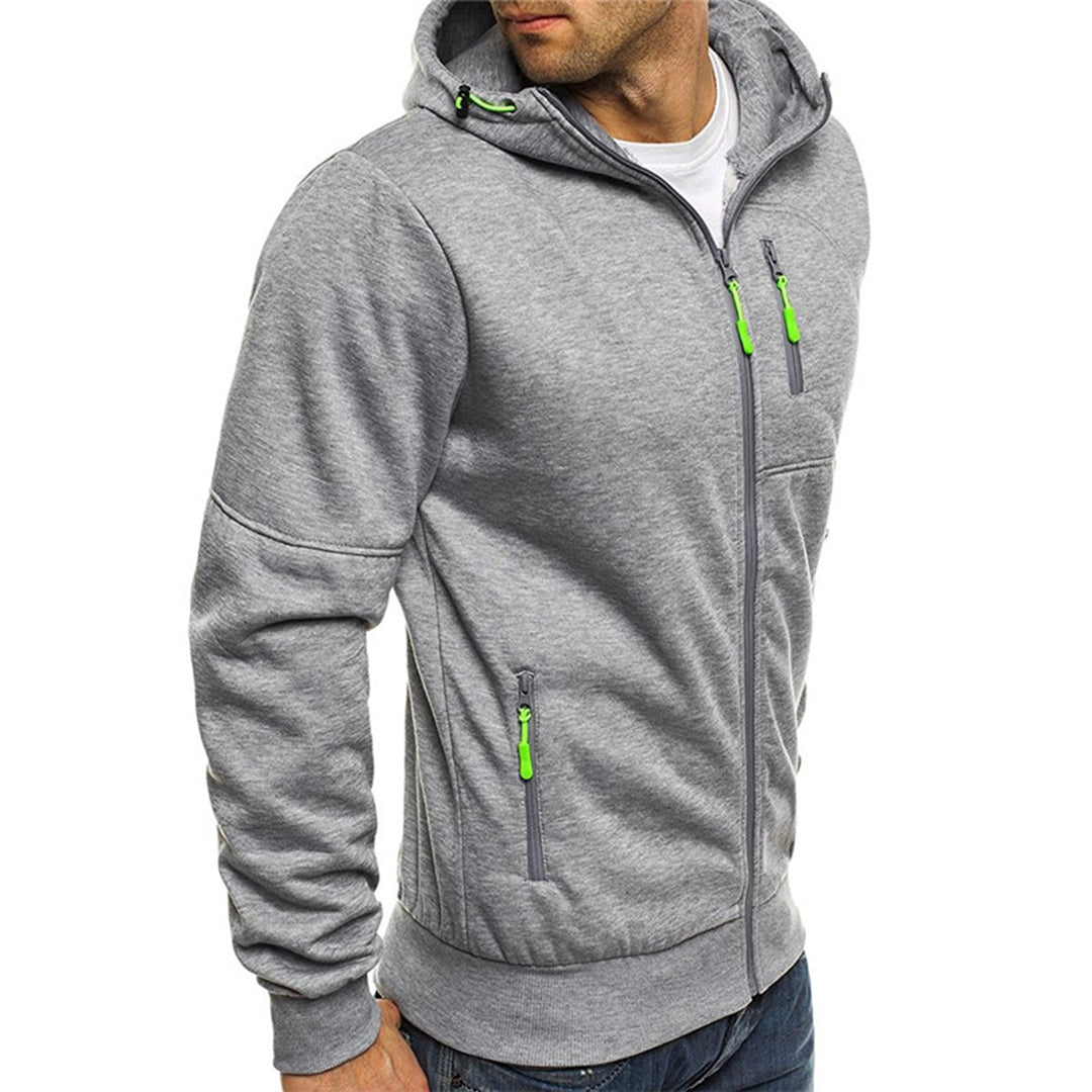 Homme portant un sweat à capuche gris avec fermetures éclair vertes, style décontracté, mode masculine, vêtement confortable, tendance automne-hiver.