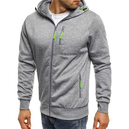 Homme portant un sweat à capuche gris avec fermetures éclair vertes, mode décontractée, vêtement tendance pour homme, style urbain moderne.
