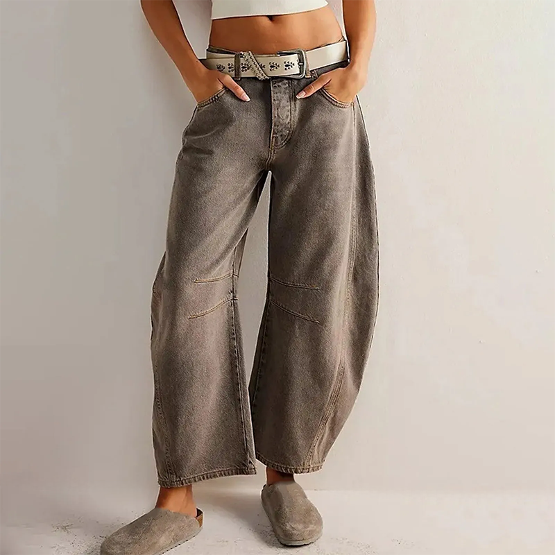 Jeans larges vintage gris pour femme, ceinture blanche, poches avant, style décontracté, tendance mode, chaussures assorties, fond neutre.