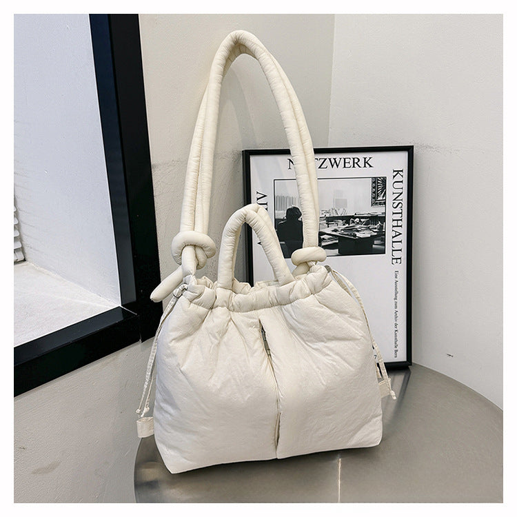 Sac à main blanc élégant avec poignées rembourrées, posé sur une table près d'une fenêtre. Accessoire de mode moderne et chic pour femmes.