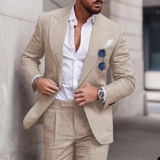 Homme en costume beige élégant, chemise blanche ouverte, lunettes de soleil bleues dans la poche, montre-bracelet argentée, style urbain chic.
