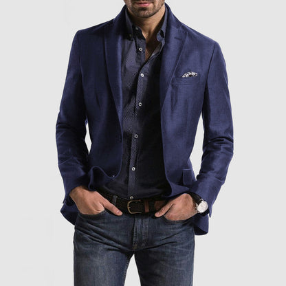 Homme portant une veste bleue élégante, chemise à motifs, jean décontracté et montre-bracelet. Mode masculine chic et moderne.