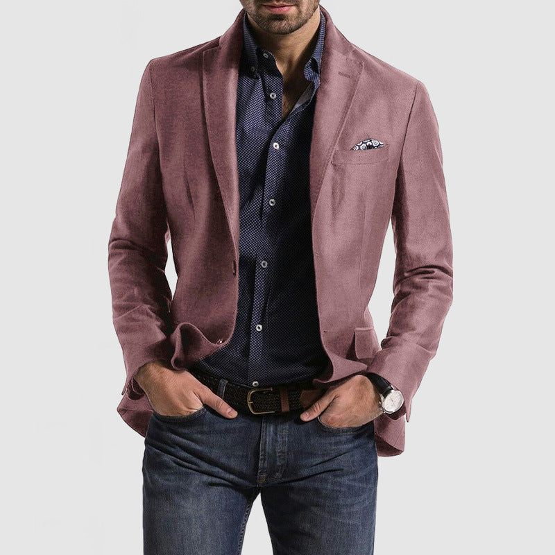 Homme portant une veste rose élégante, chemise bleue à motifs, jean décontracté, montre-bracelet et pochette, mode masculine chic et moderne.