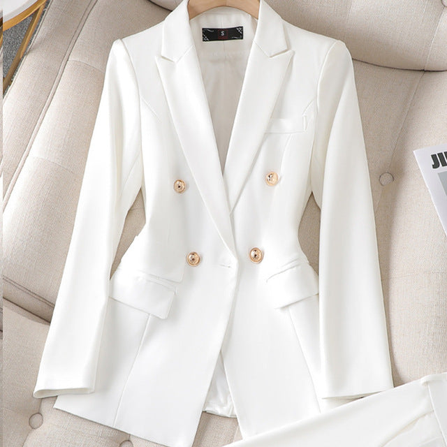 Blazer blanc élégant à double boutonnage, posé sur un fauteuil beige. Veste de costume moderne pour femme, style chic et professionnel.