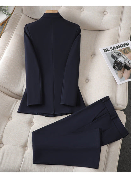 Costume bleu marine élégant pour homme, veste et pantalon, posé sur un canapé beige avec un magazine de mode à côté.