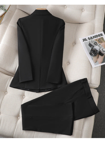 Costume noir élégant pour homme posé sur un canapé beige, avec un magazine de mode à côté. Vêtements formels, style classique, mode masculine.