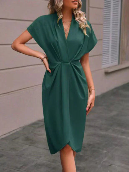 Robe verte élégante avec manches courtes, col en V, portée par une femme. Mode féminine chic, tenue de soirée tendance, style moderne.
