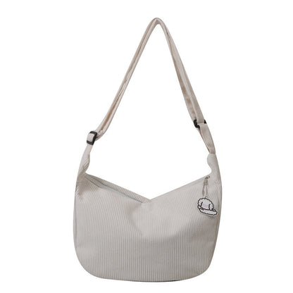 Sac à bandoulière beige en toile avec motif brodé, design minimaliste, idéal pour un style décontracté. Accessoire mode tendance et pratique.