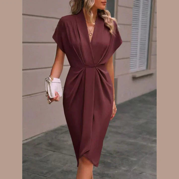 Robe élégante bordeaux avec manches courtes, col en V, portée par une femme tenant un sac à main blanc. Mode féminine chic et tendance.