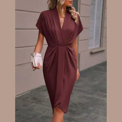 Robe élégante bordeaux avec manches courtes, col en V, portée par une femme tenant un sac à main blanc. Mode féminine chic et tendance.